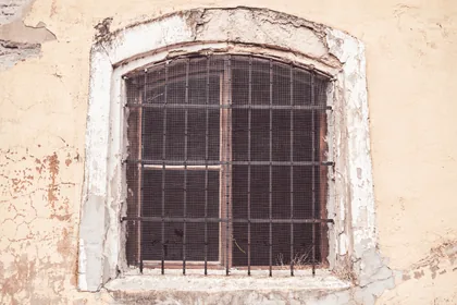 Vergittertes Fenster in ockerfarbener Wand